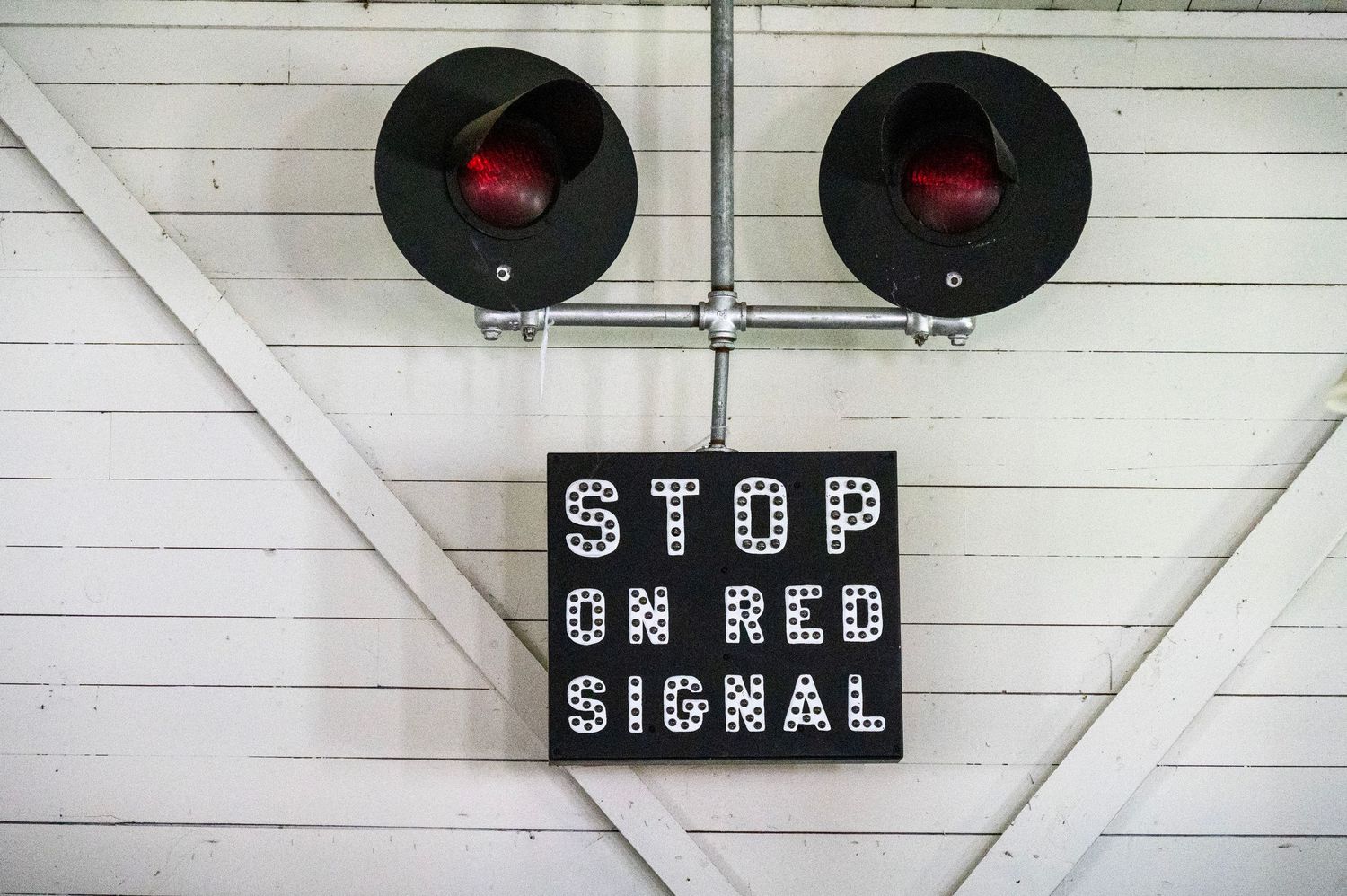 A row of black stop signal lights mounted on a white wooden wall with horizontal siding.