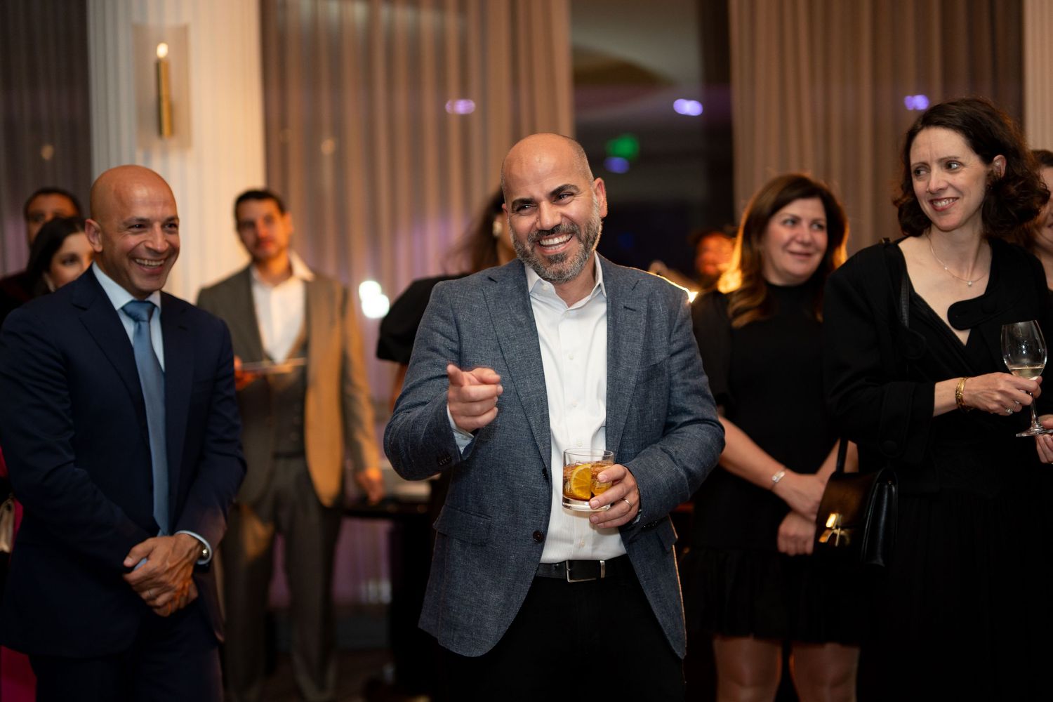 A group of people dancing and celebrating at an elegant indoor reception event at Boston's Four Seasons Hotel.