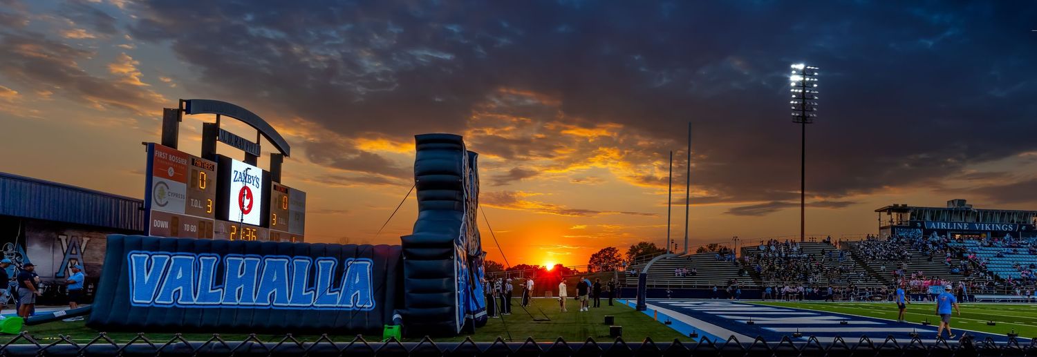 Wide panoramic view of Bill Snyder Family Stadium at Kansas State University during a vibrant sunset with dramatic clouds.