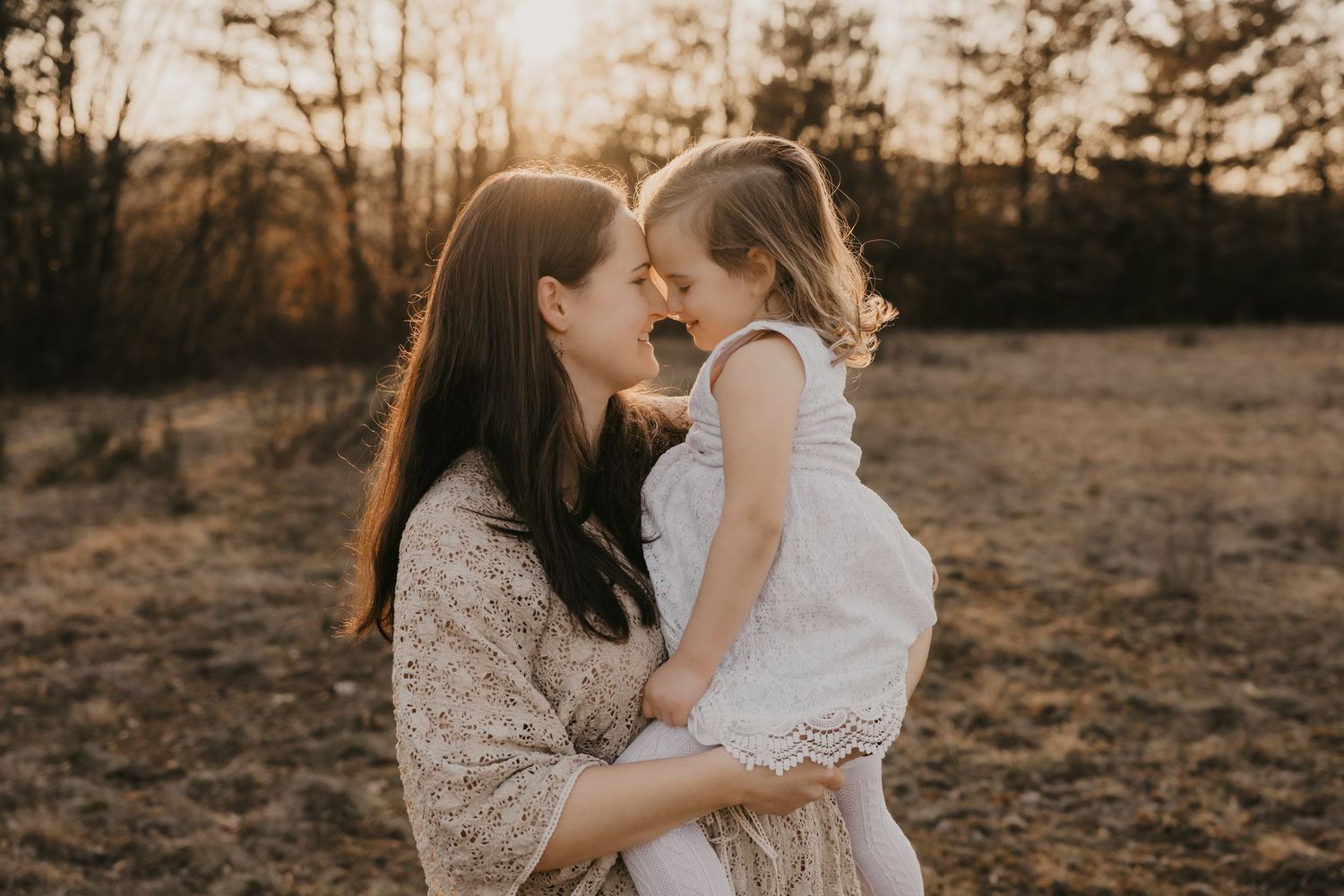 Romantic couple embraces in a sun-drenched field during golden hour as sunlight creates a dreamy atmosphere.