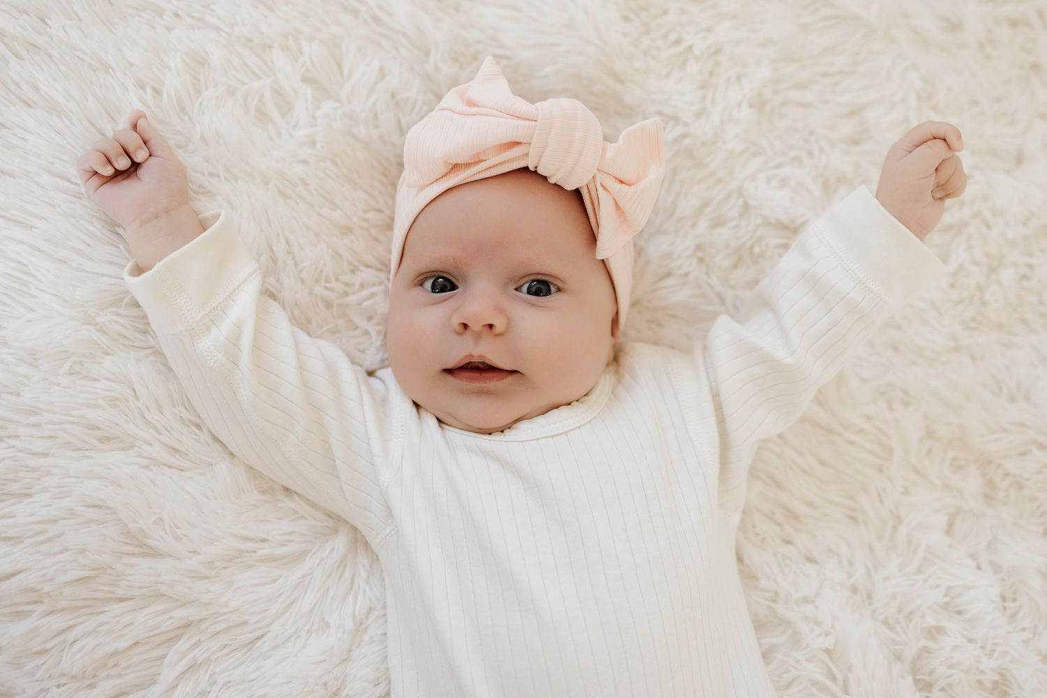 4 week old baby looks into the camera on a white background