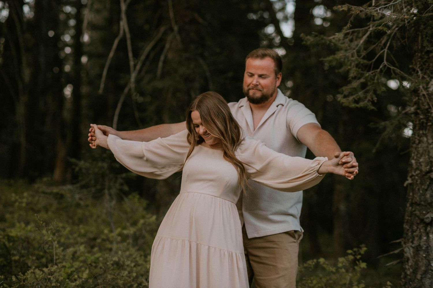 Couple holding hands while walking on a path, woman in white lace dress and man in khaki pants and sneakers.