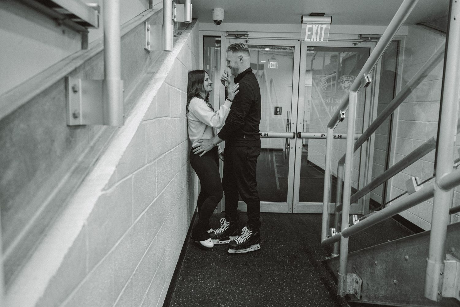 engagement shoot with couple embracing just outside ice skating rink
