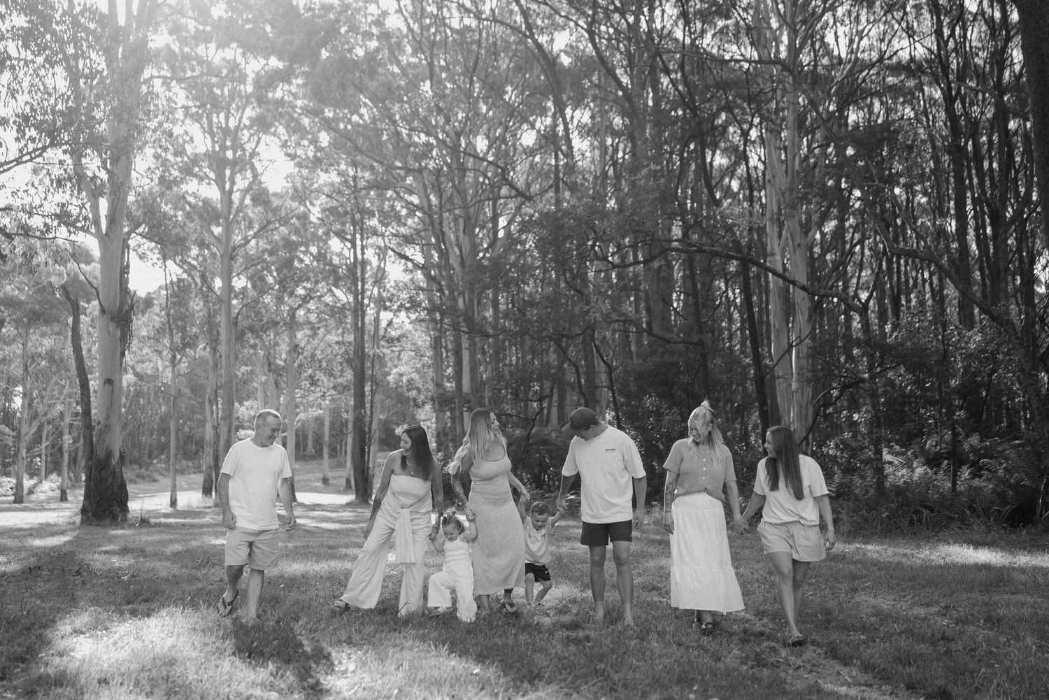 A group in white outfits walks together across a sunlit field.