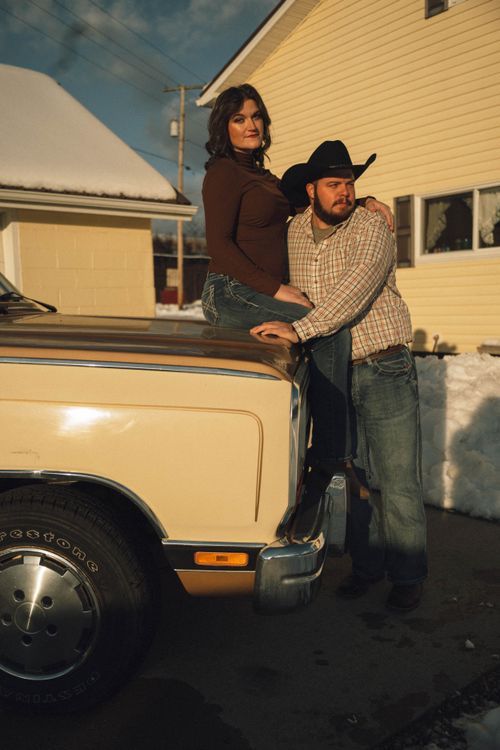Western-style couple posing on a vintage truck for couple's portraits