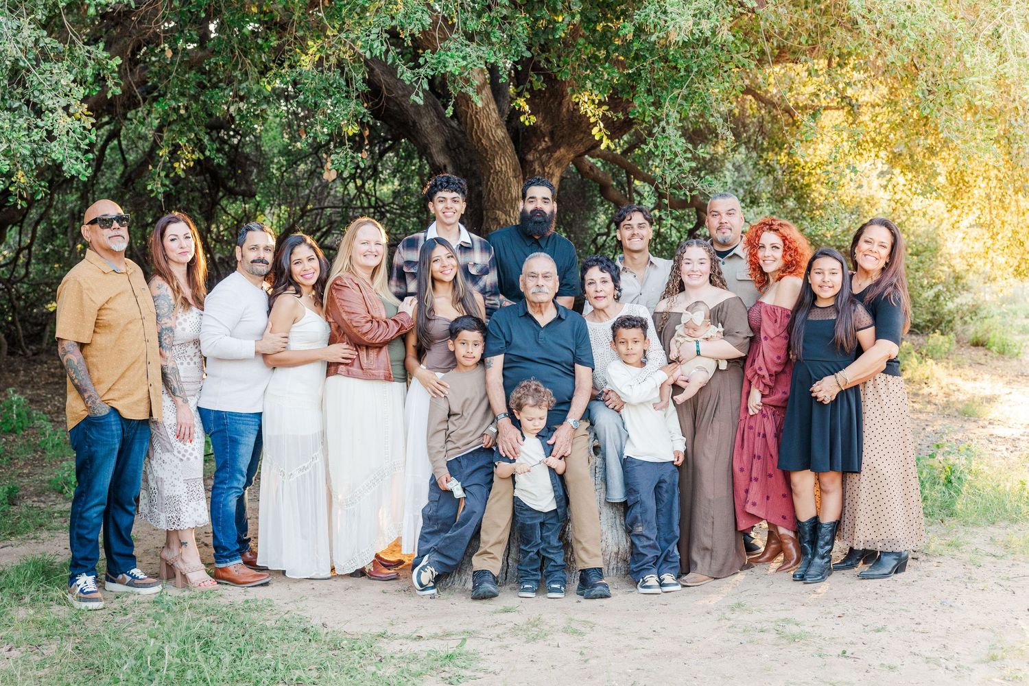 A group of people in coordinated casual outfits pose together outdoors during a fall photoshoot.