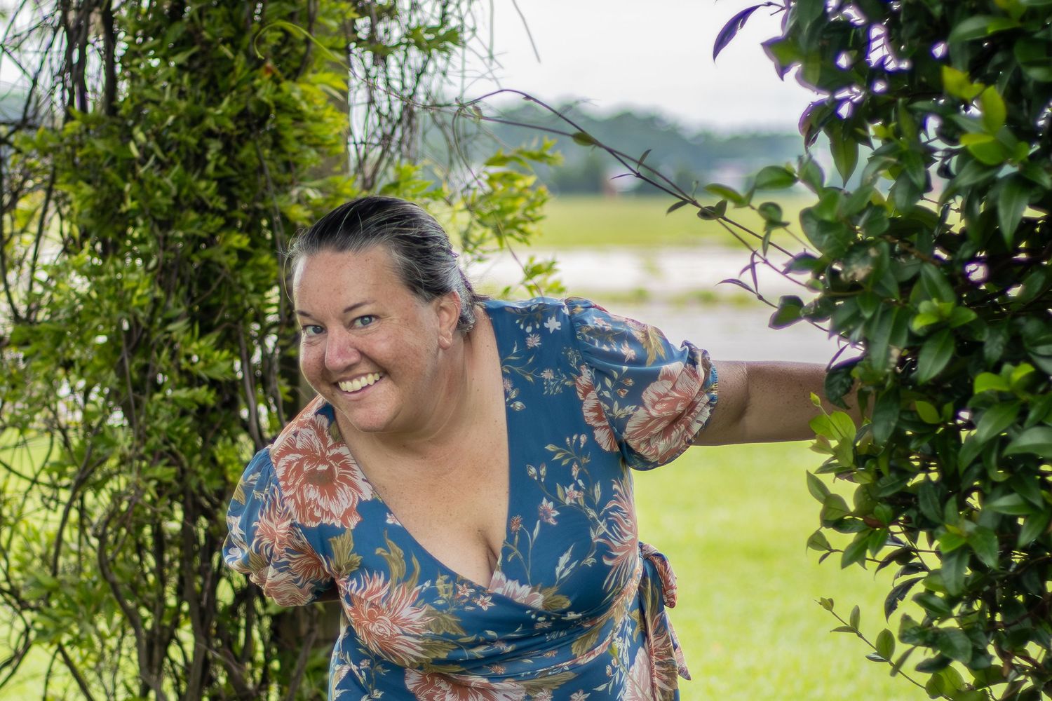 A person wearing a floral dress stands under a leafy garden arch on a sunny summer day.
Senior Photos Graduation family photography spring