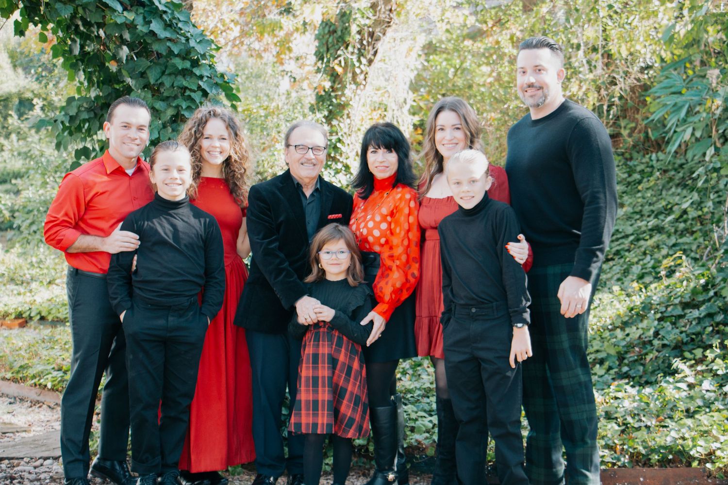 A family in coordinated green and white outfits poses together outdoors during a fall photo session.
