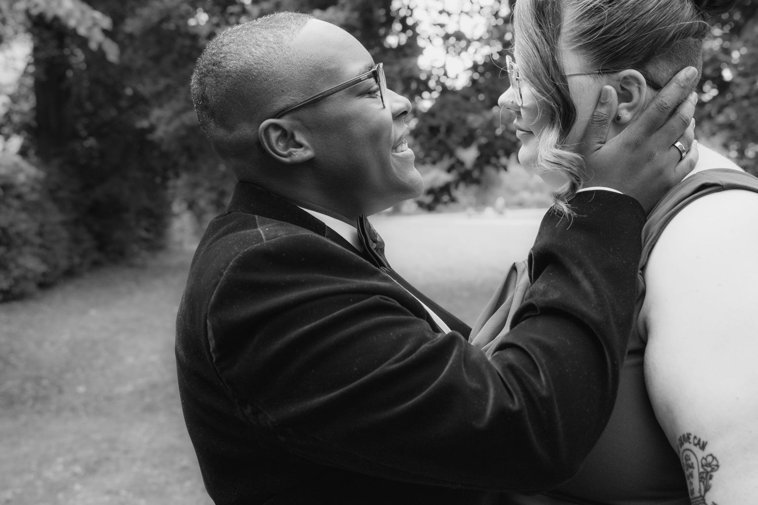 Black and white photo of a bride tenderly cupping her brides face during an emotional outdoor wedding moment.