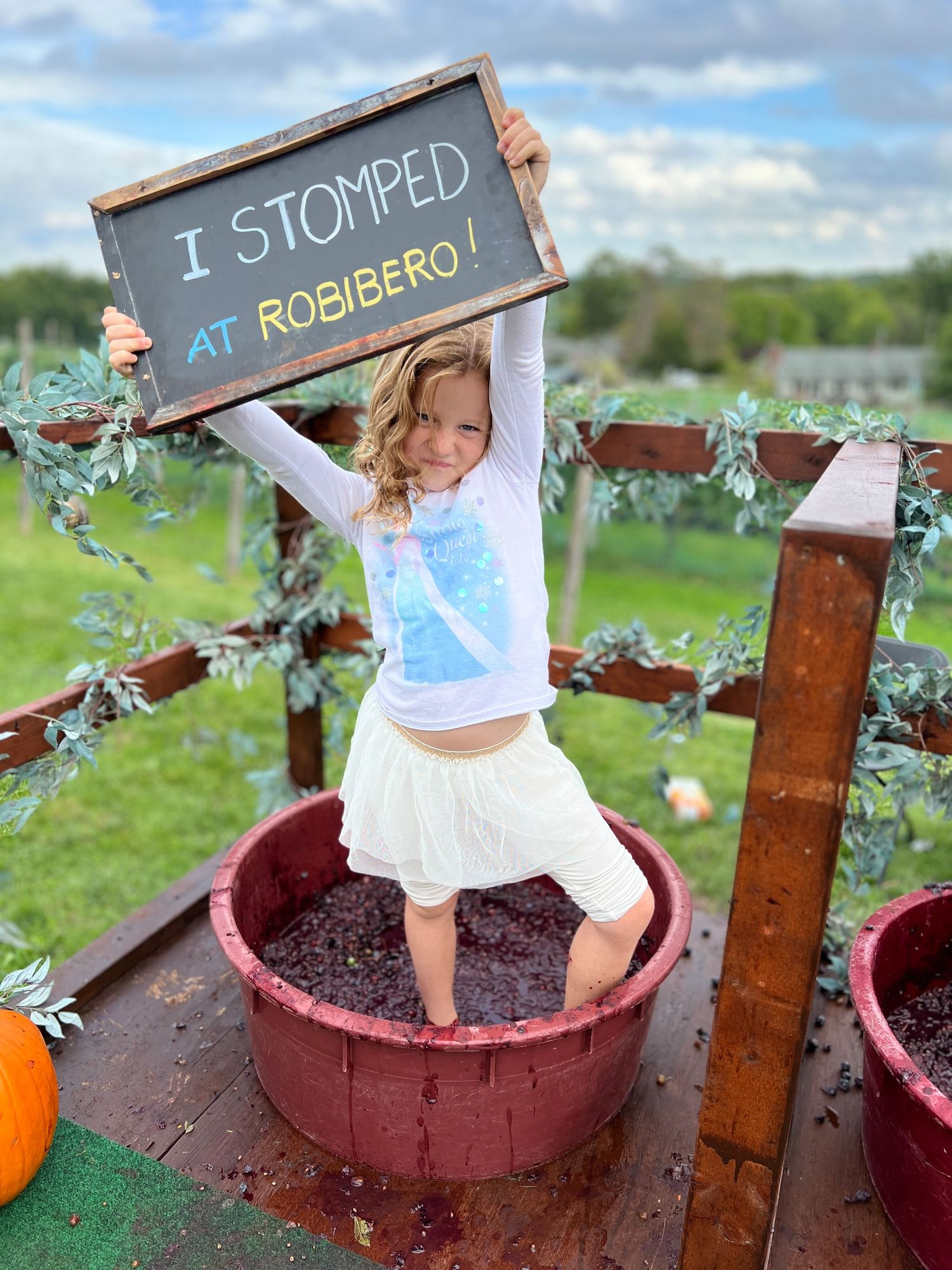 A sequence of photos showing feet stomping on soil in rustic red planters with wooden garden markers in an outdoor setting.