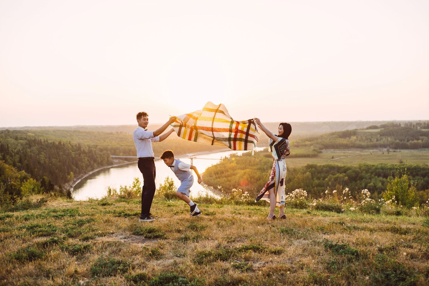 Family of four posing at golden hour sunset on a hilltop, wearing coordinated cream and white outfits.
