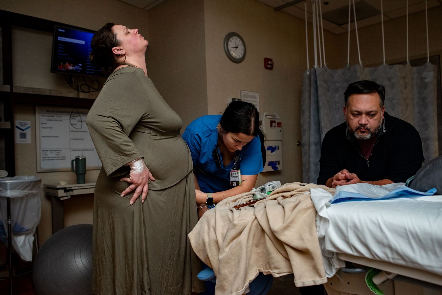 Healthcare workers in scrubs and protective gowns perform medical procedures in a clinical setting.