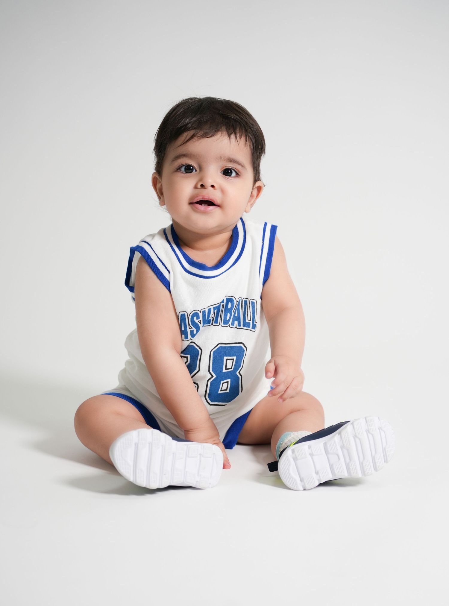 Baby enjoying a cake smash photoshoot Dubai session in a studio setup with colorful props and a professional photographer capturing moments.