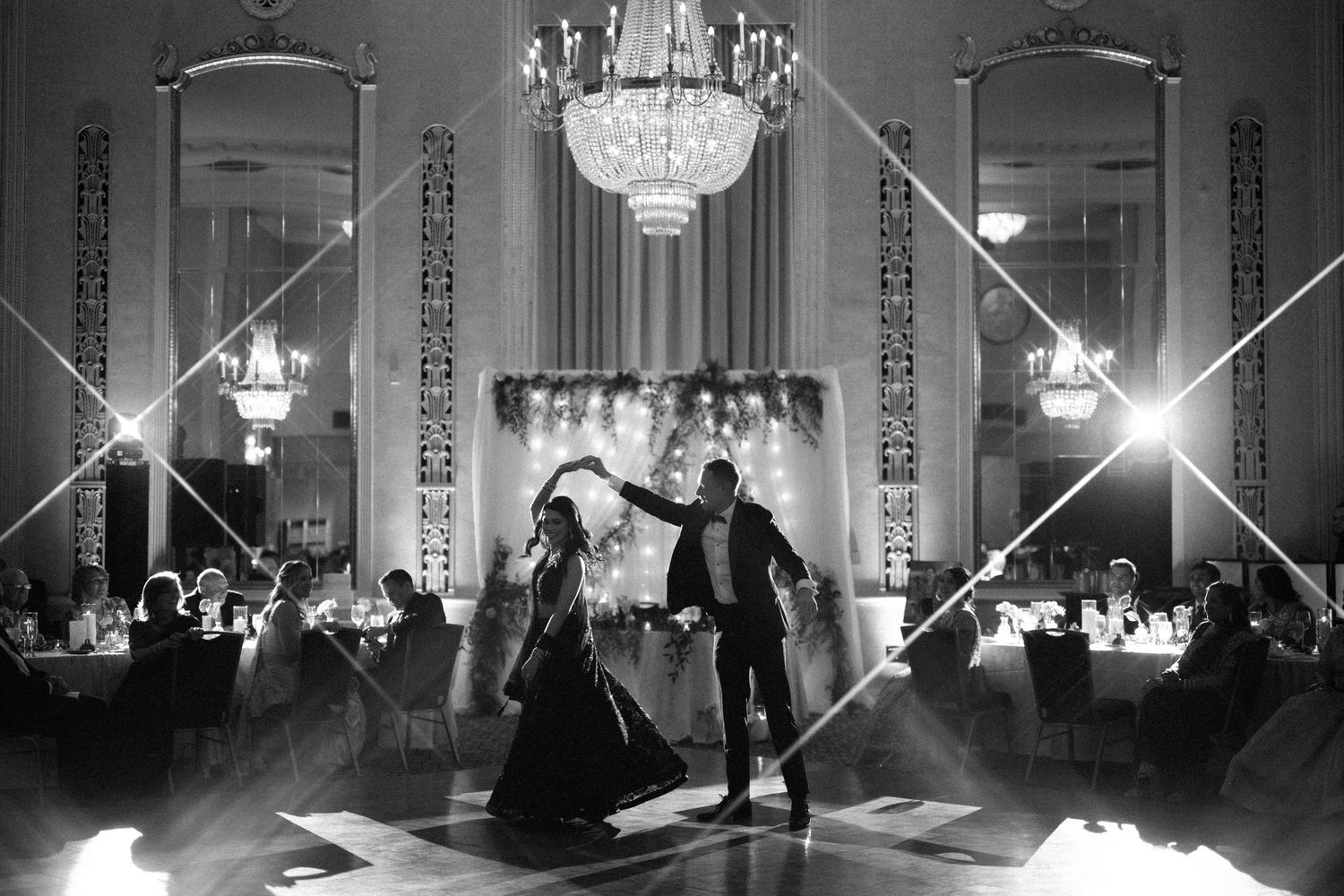 Dancing couple surrounded by elegant white pillars and grand wooden doors of a historic government building.