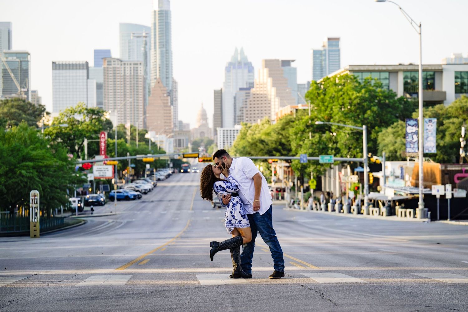 Couple sharing a romantic dip kiss on a city street with Austin Texas skyline in the background.