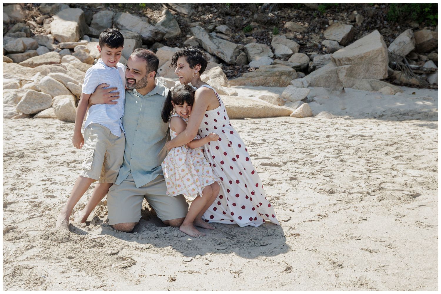 Hyatt Ziva Puerto Vallarta Family Photographer capturing parents embracing their two children during a beach family photo session.