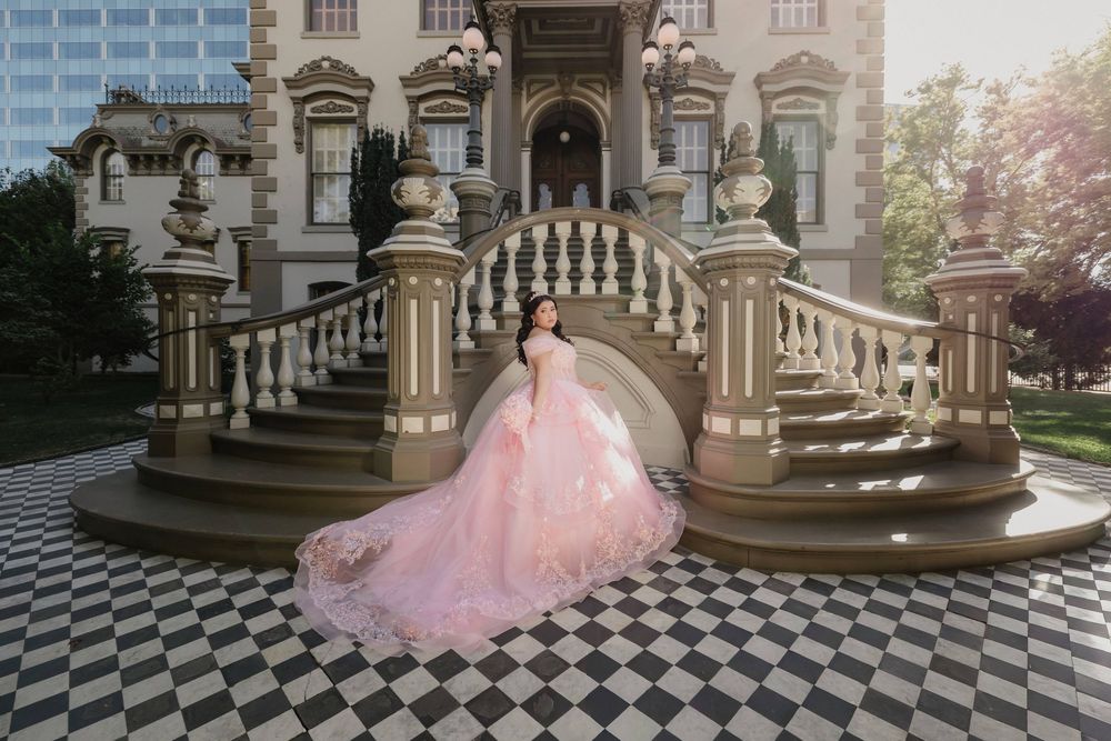 Quinceanera in red ballgown quince dress with floral details and crown poses in a church for quince ceremony.