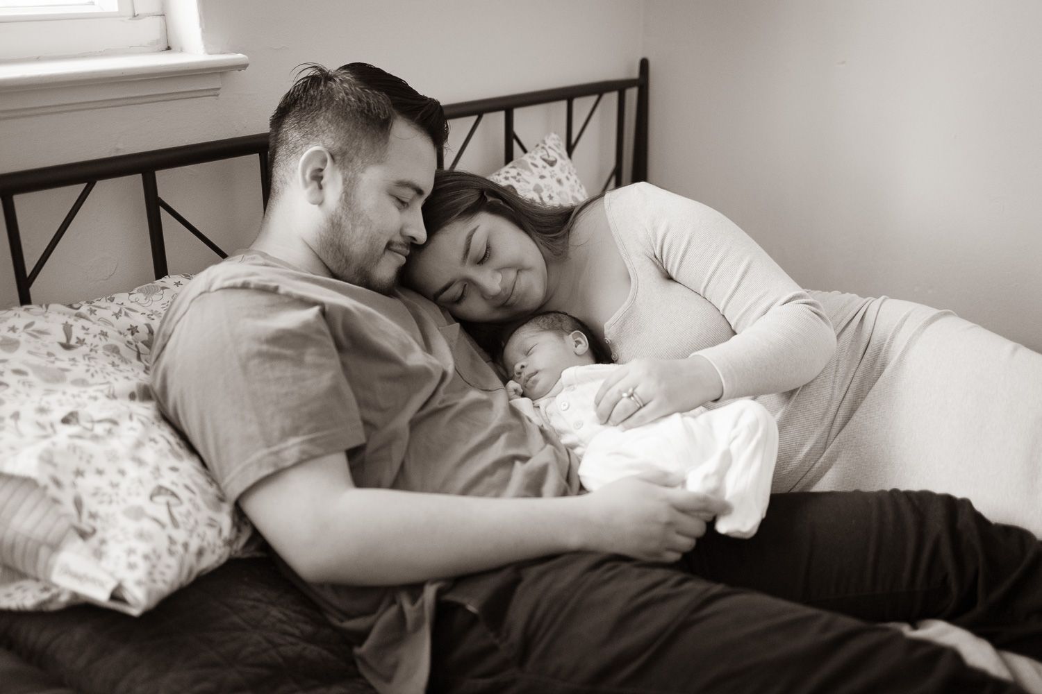 Family snuggles with baby at lifestyle newborn photo session with Bay Area Newborn Photographer Cindy Tucey in Campbell