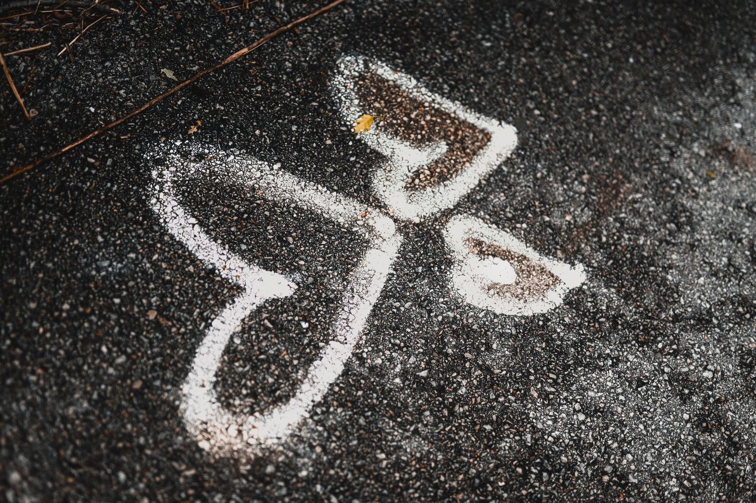 Angel figure drawn with white sugar or salt on dark asphalt pavement, forming a heart and wing shape.