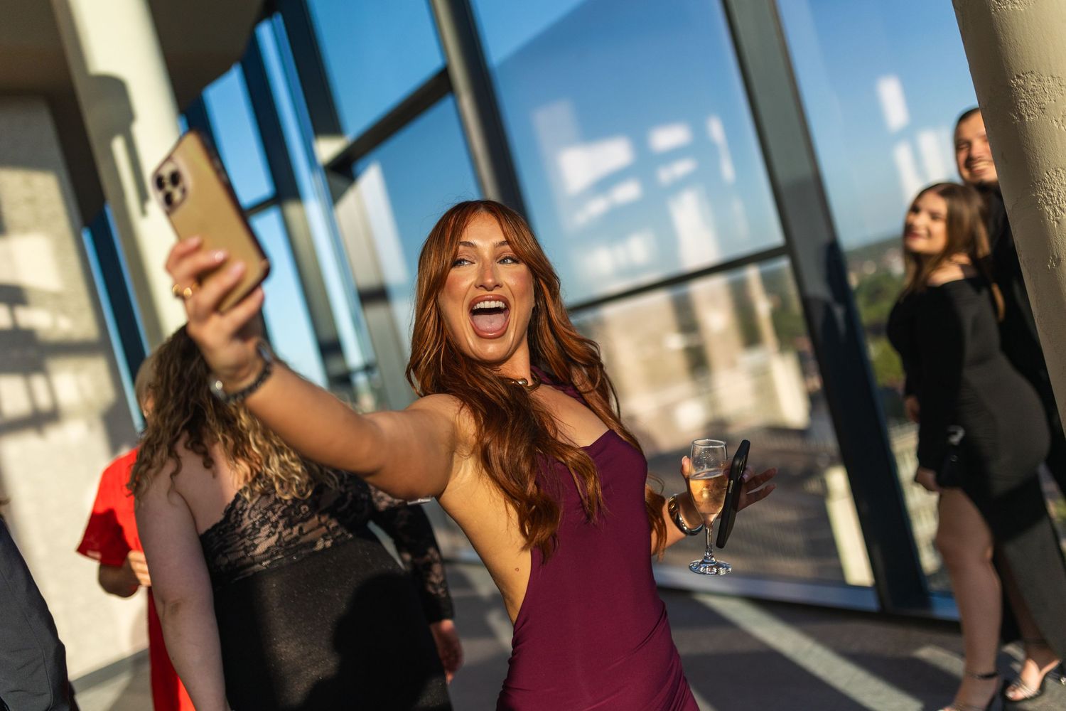 Three friends taking selfies and having fun in a modern building with large windows and natural lighting.
