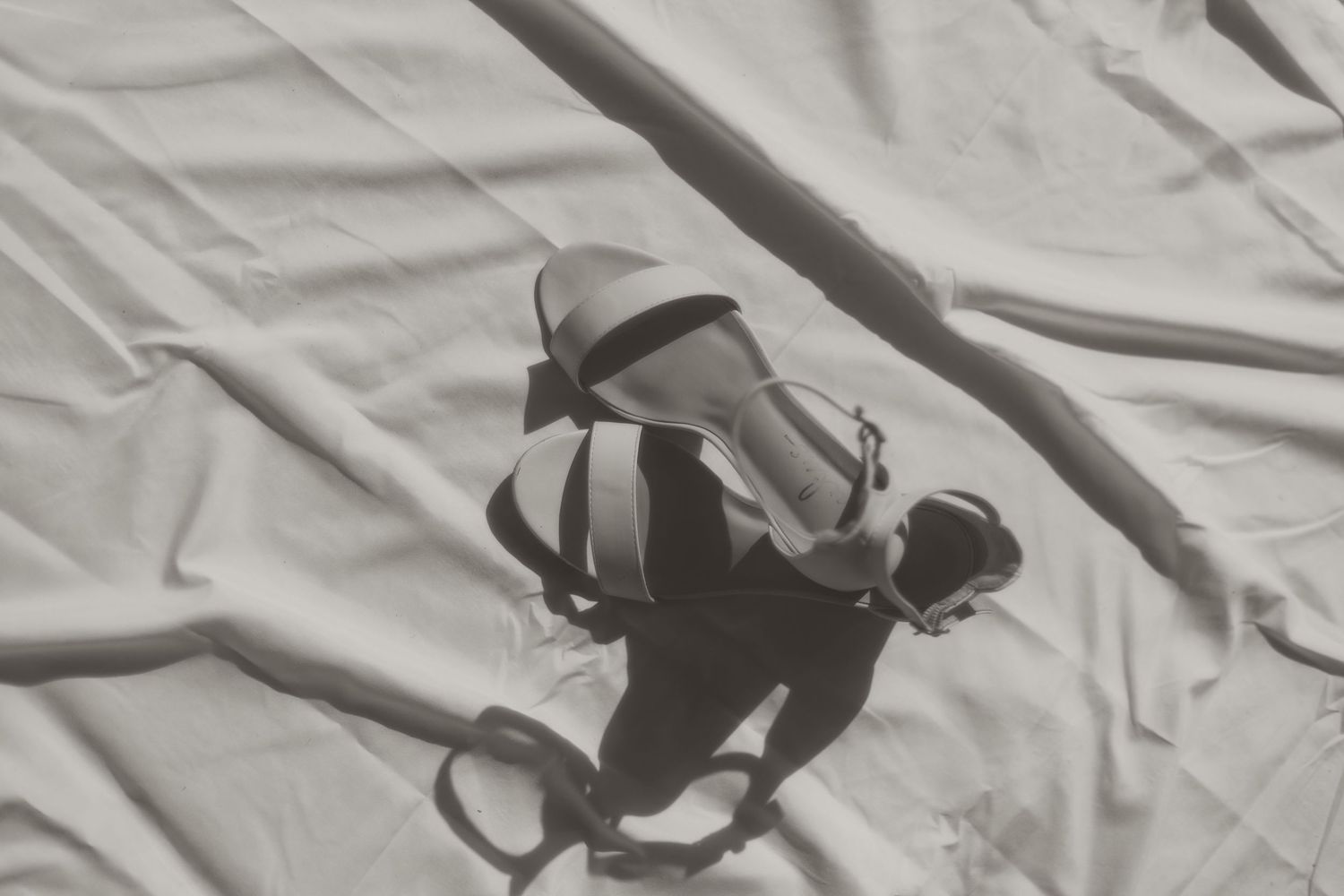 Aerial black and white view of a skateboarder performing a trick with shadow cast on light fabric below.