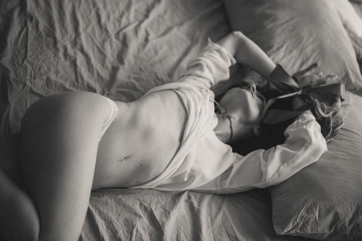 Woman lying on bed in natural light, relaxed boudoir photography in Amsterdam