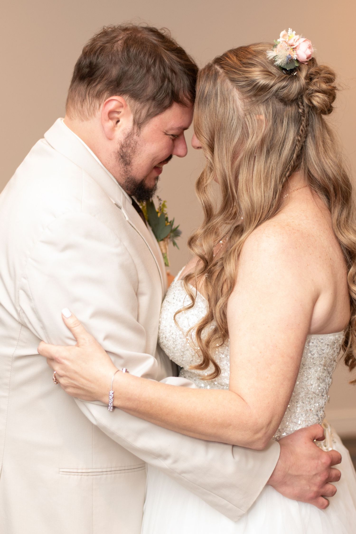 A romantic couple in wedding attire sharing an intimate moment, with the bride wearing a sparkly dress and delicate flowers.