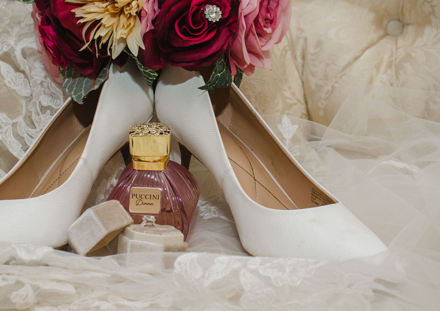 Wedding details with pink and burgundy flowers arranged next to delicate accessories.