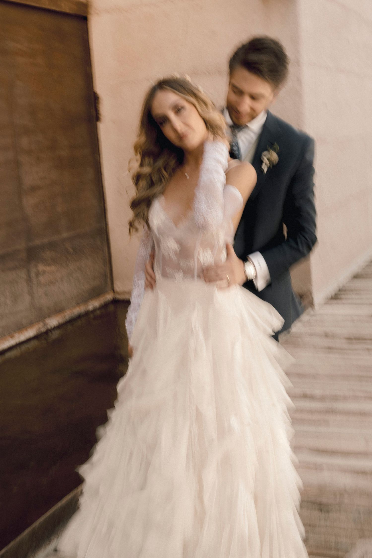 Artistic motion blur wedding portrait with layered tulle gown and navy suit.