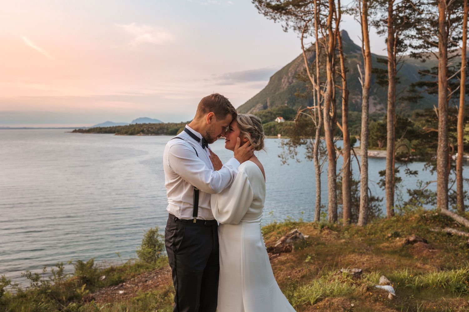 Sunset wedding portrait among coastal pine trees with mountain view.