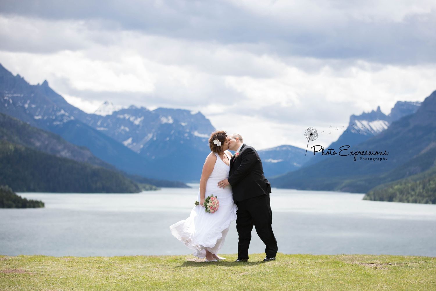 Scenic mountain landscape photo with lake and cloudy sky backdrop.