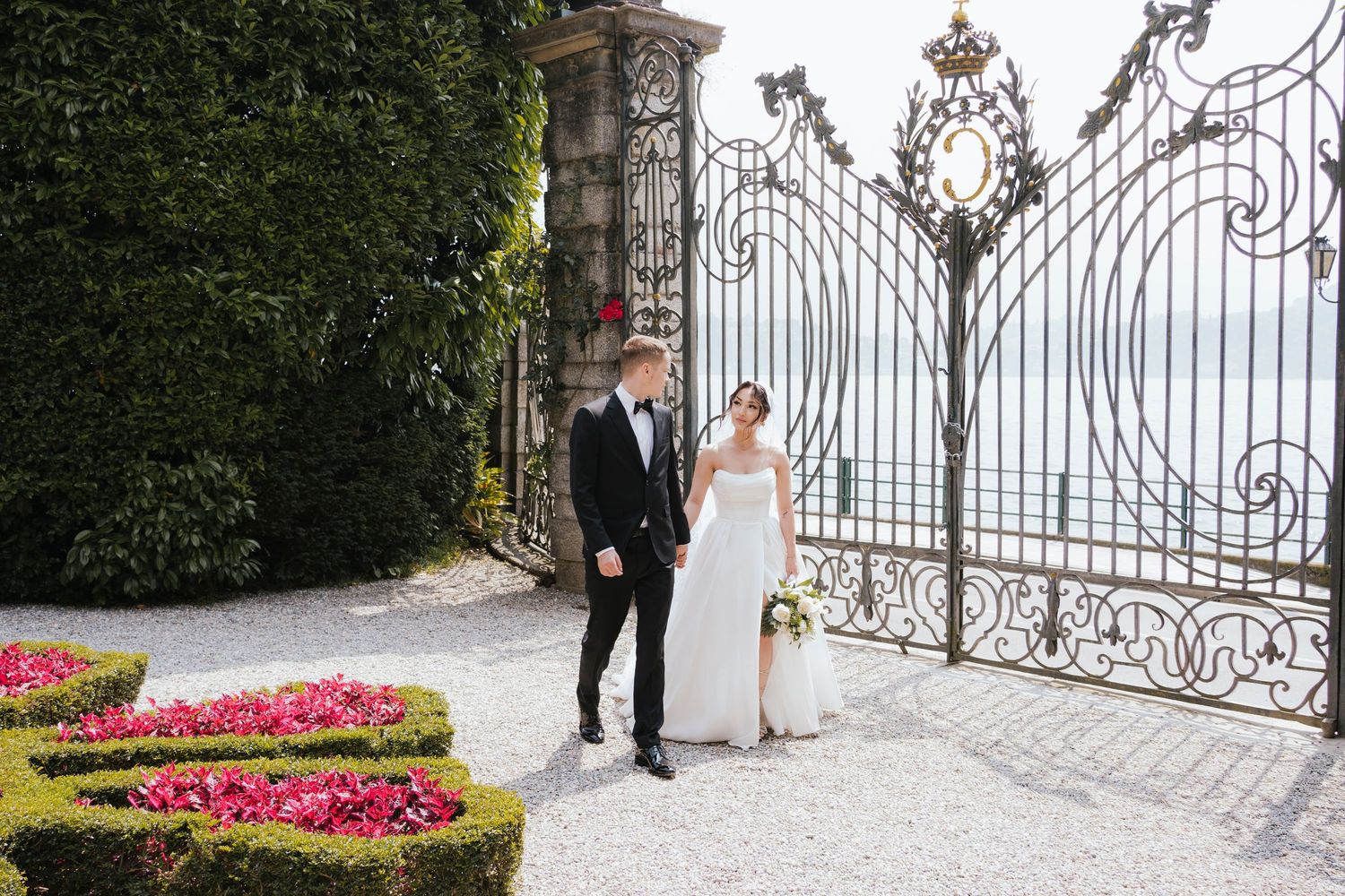 Classic wedding portraits captured at ornate white iron gates with floral gardens.