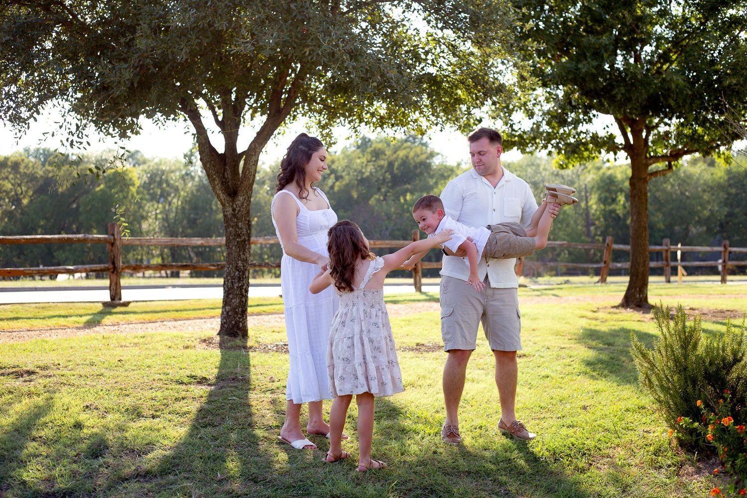 A family plays together in a sunny park with trees in the background.
