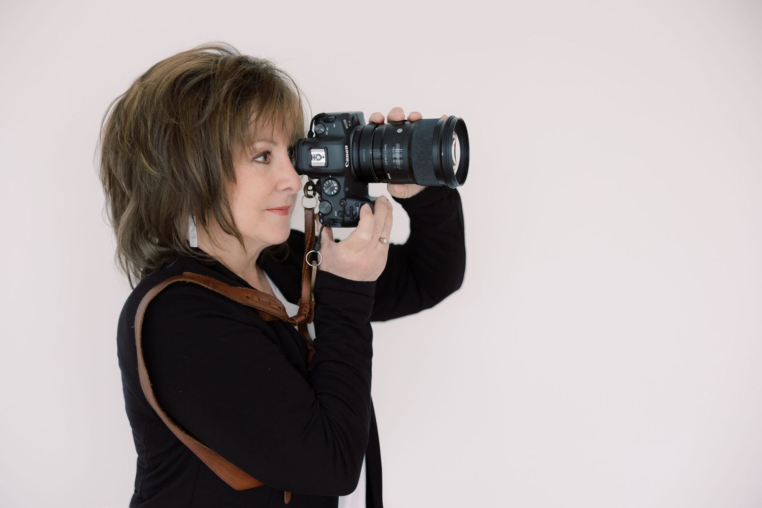 Photographer looking through the lens of a camera on a white background
