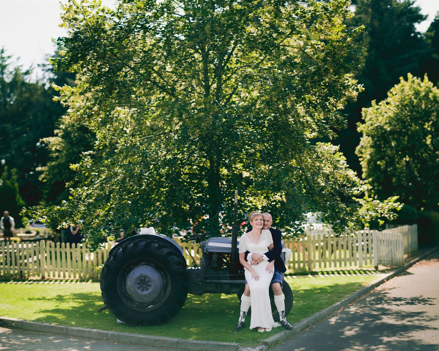 A vintage tractor serves as a backdrop for a countryside wedding photo session.