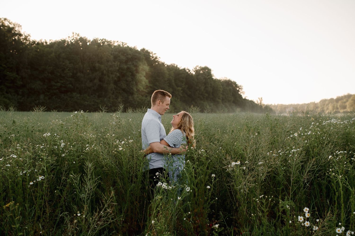 Romantic couple embracing in a wildflower meadow at sunset.