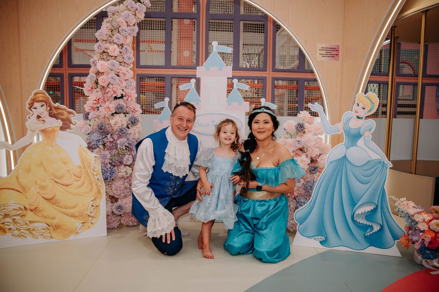 Themed party setup with princess decorations and characters in an arched room.