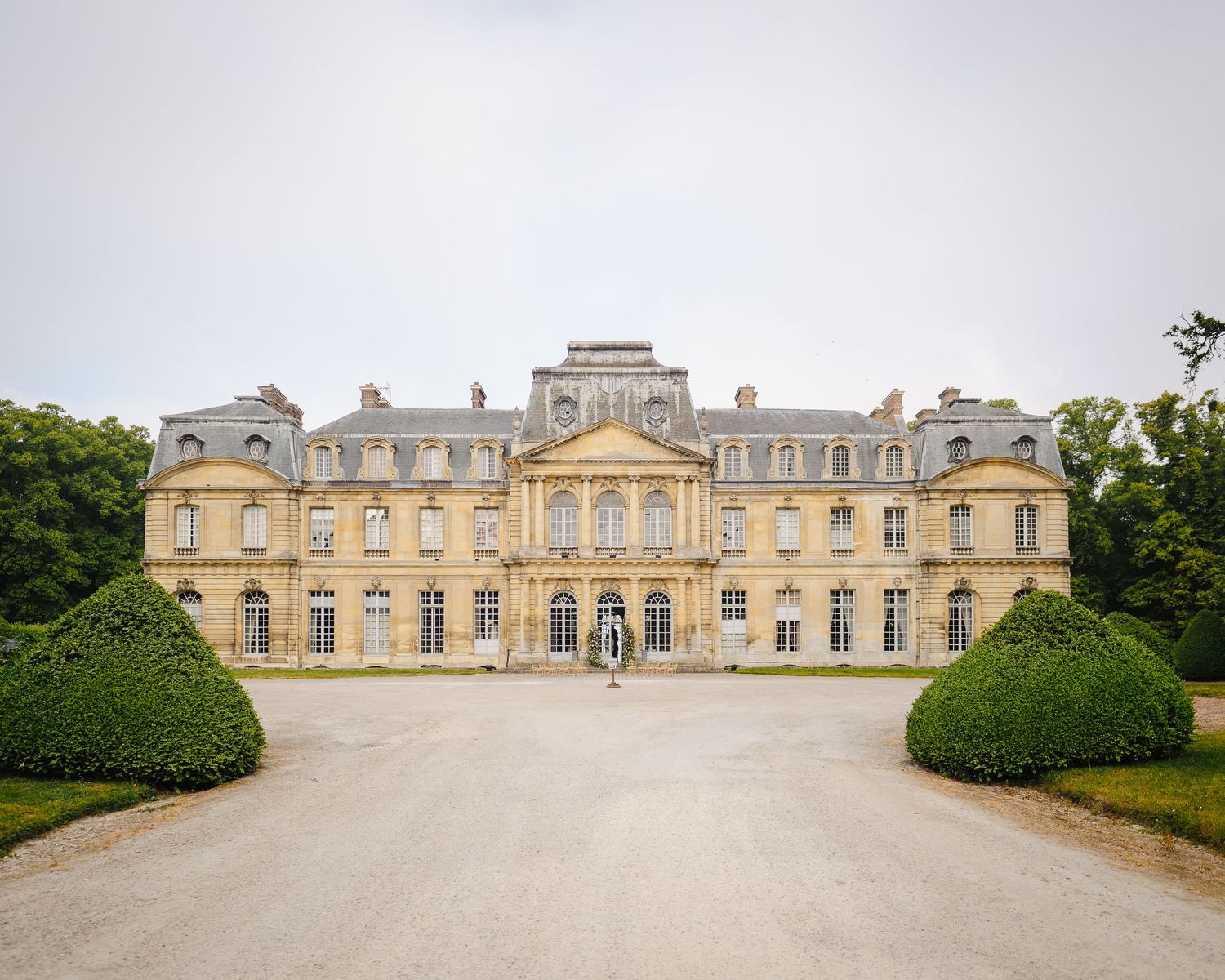 Panoramic exterior view of an elegant French chateau with symmetrical architecture and manicured gardens.