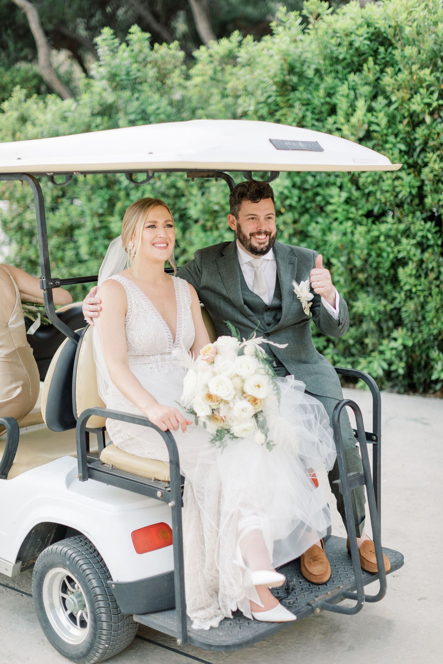 A couple riding in a golf cart after their wedding ceremony.