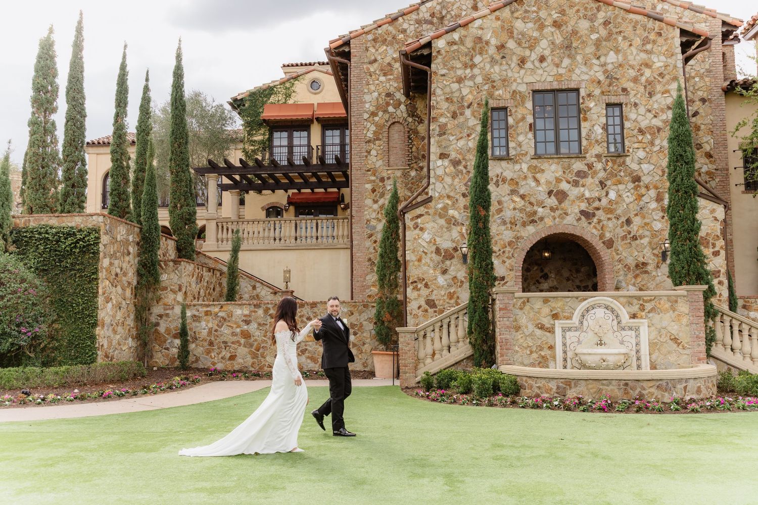 A collection of outdoor wedding photos at a rustic stone venue with cypress trees and manicured lawns.