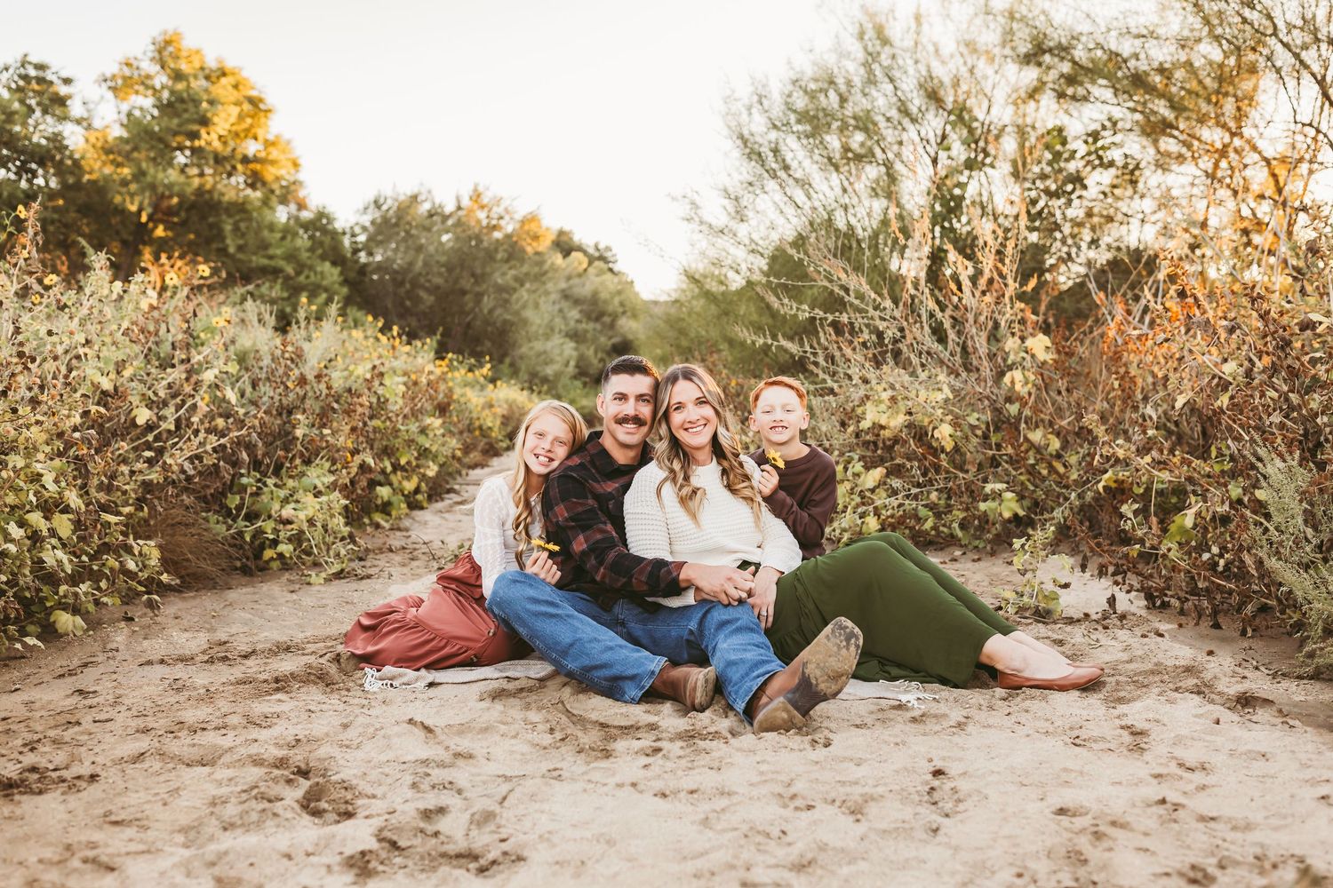 A family shares tender moments together in a natural outdoor setting during golden hour.