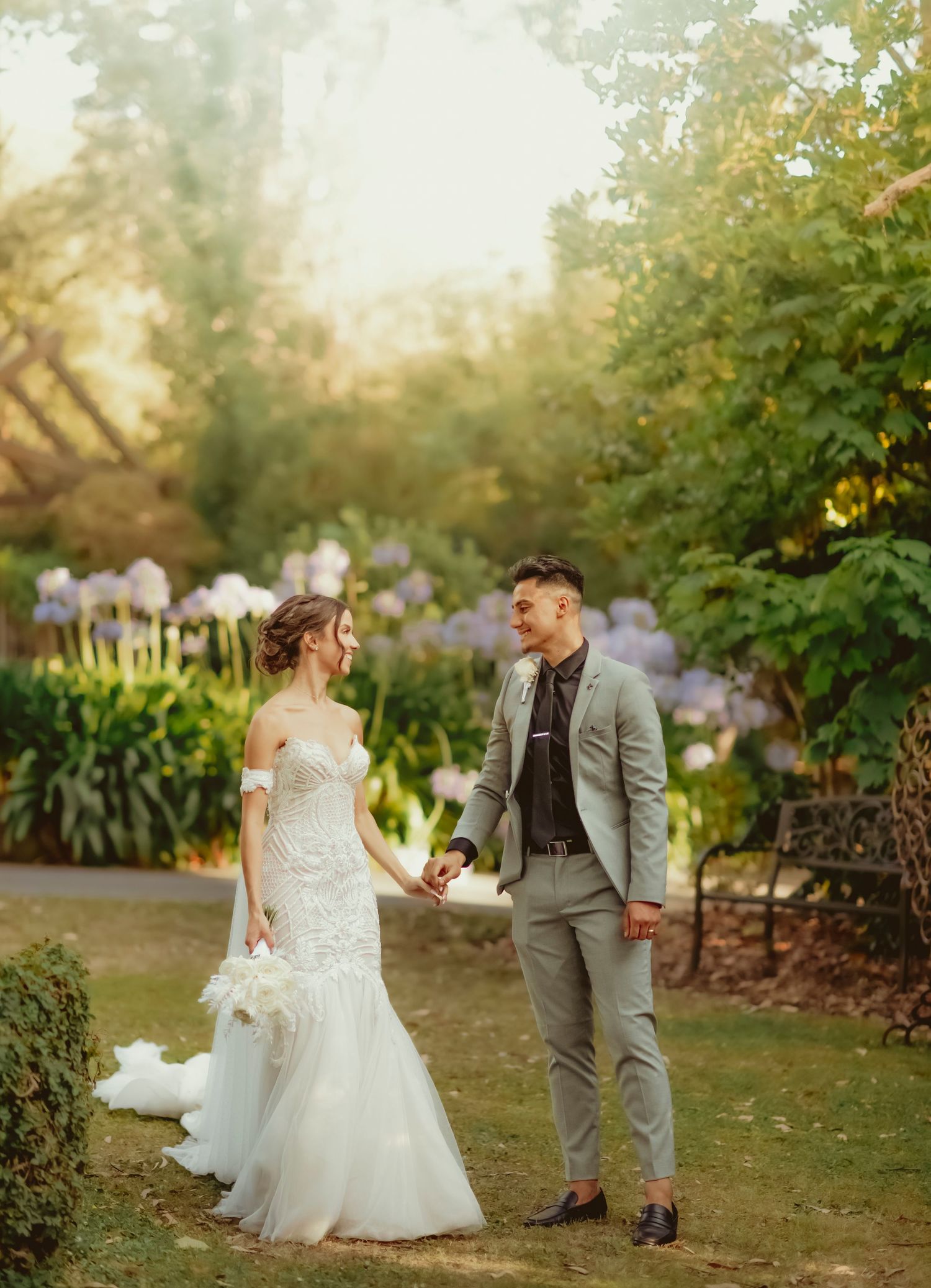 A couple shares a romantic moment in a lush garden setting during golden hour while wearing wedding attire.