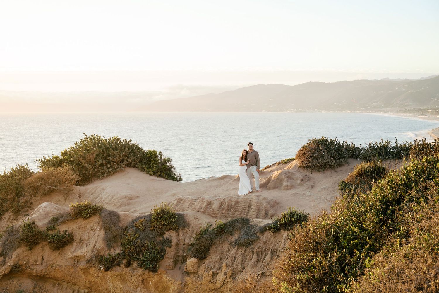 Coastal landscape with rolling hills and cliffs overlooking the ocean during golden hour.