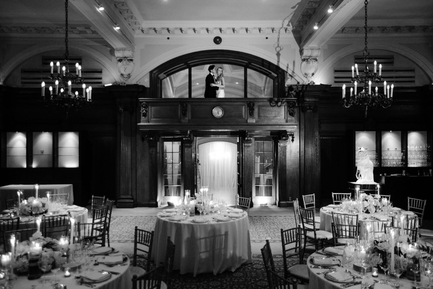 Elegant ballroom with crystal chandeliers and round tables set for a formal wedding reception.