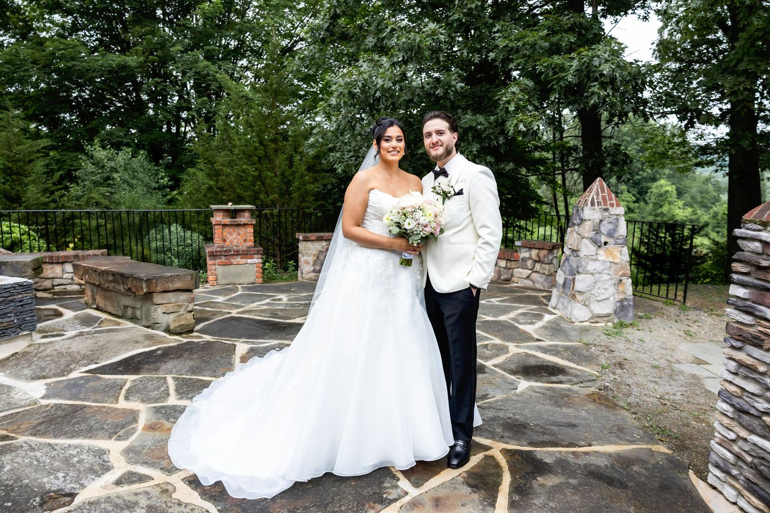 A dance sequence captured on a stone patio with trees and greenery in the background during a wedding celebration.