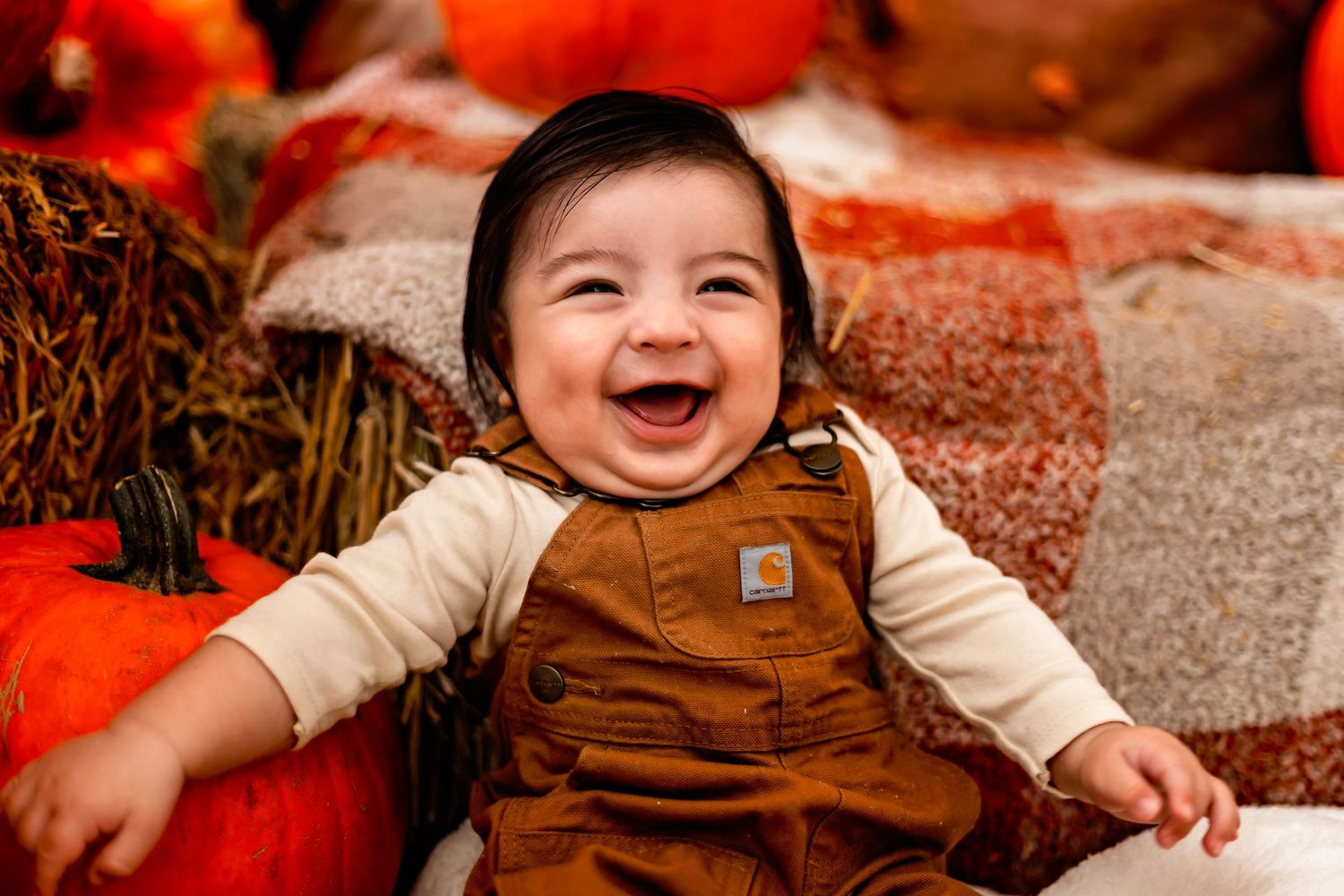 A joyful scene at a pumpkin patch features overalls and bright autumn hues during a seasonal photo session.