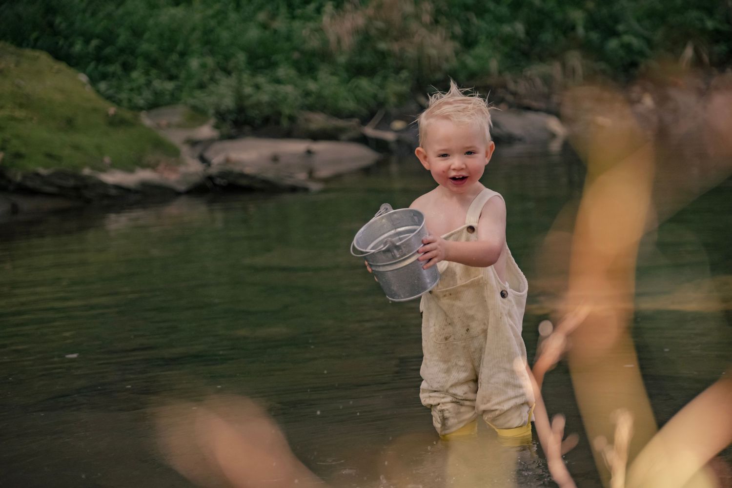 A playful scene by a lake with people splashing and enjoying the water.