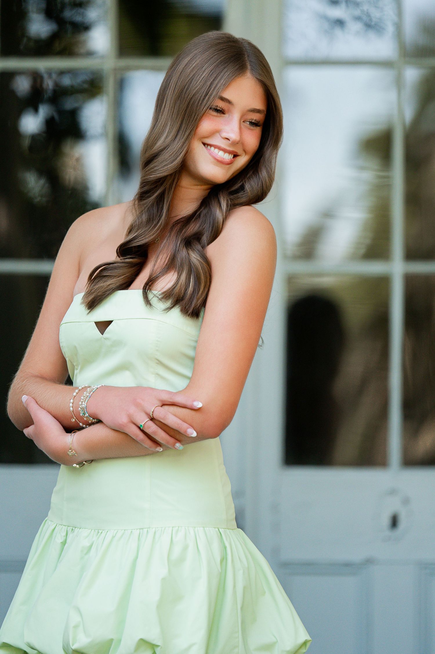 Portrait of someone wearing a mint green dress against a white building.