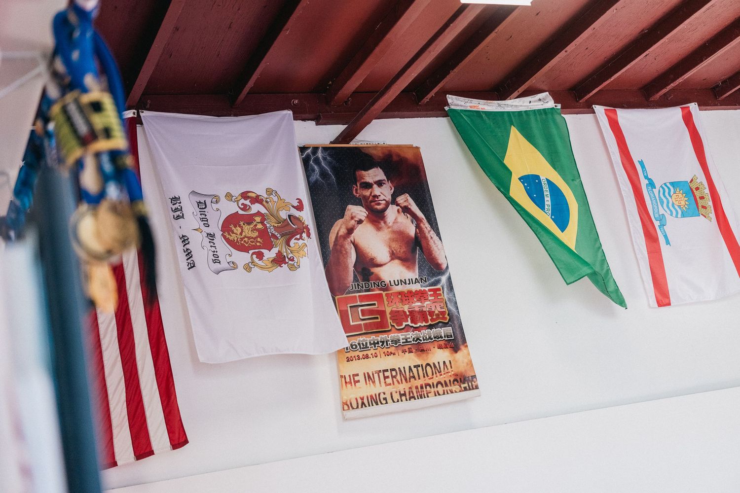 Colorful international flags and banners hang from a ceiling in an indoor space.