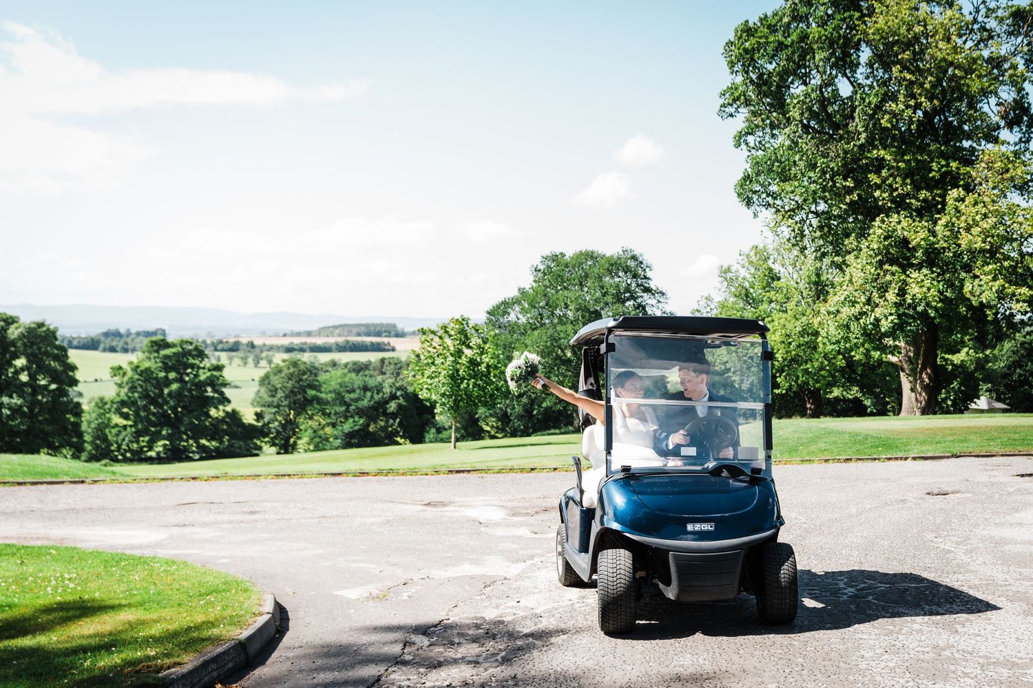 Wedding couple in a golf buggy at Murrayshal country estate.  Views over the golf course and perthshire countryside in background.